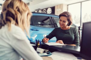 Eine Frau unterschreibt einen Kaufvertrag für ein Auto.